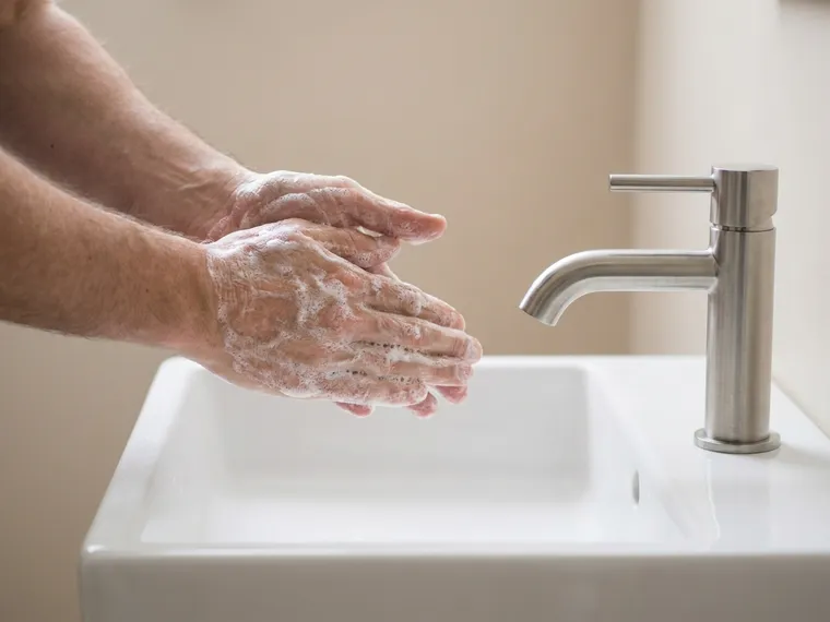 Mãos ensaboadas com espuma sob a torneira